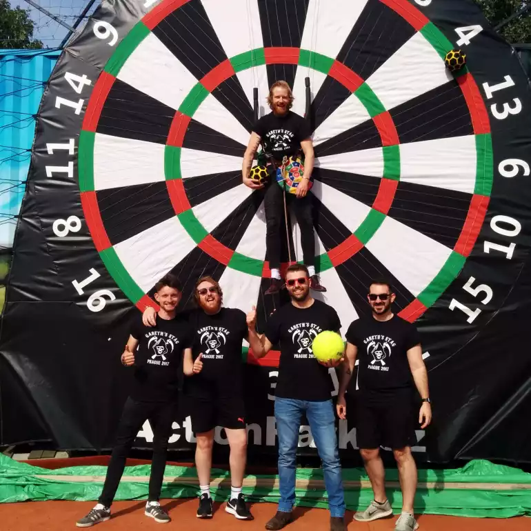 Group of friends after enjoying foot darts during their bachelor party in Prague with the groom to be in the middle of the target.