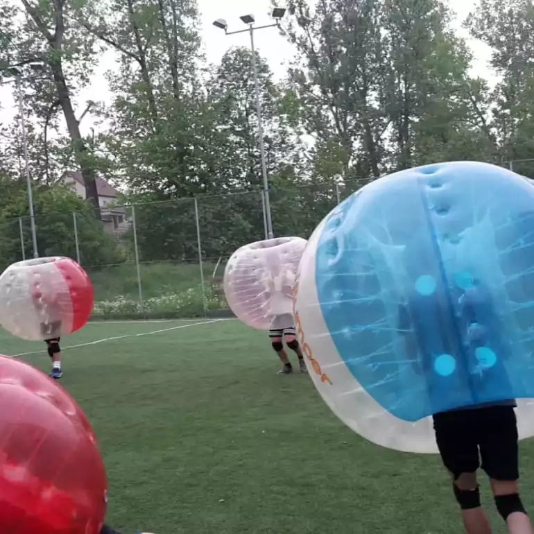 People playing bubble football outdoors in inflatable bubbles.