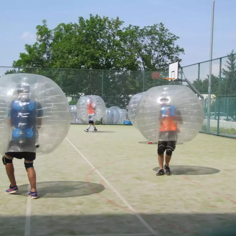 Two guys playing football in inflatable bubbles.