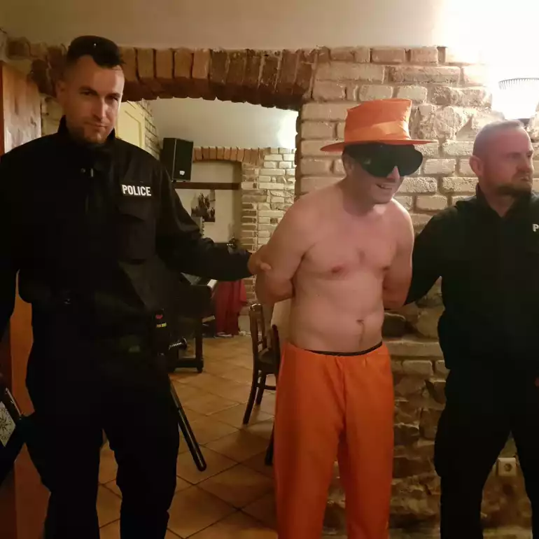 Guy dressed up in costume and handcuffed between 2 guys.